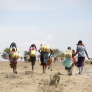 Women often have to walk long distances to collect water for their families and often arrive to a crowded source and must wait in line for the chance to fill their jerry cans.